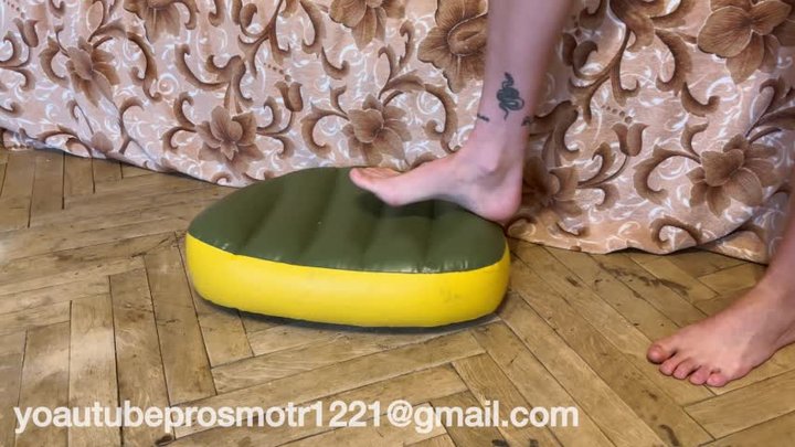 Nastya tramples the inflatable pillow with her bare feet, stands on it with all 
