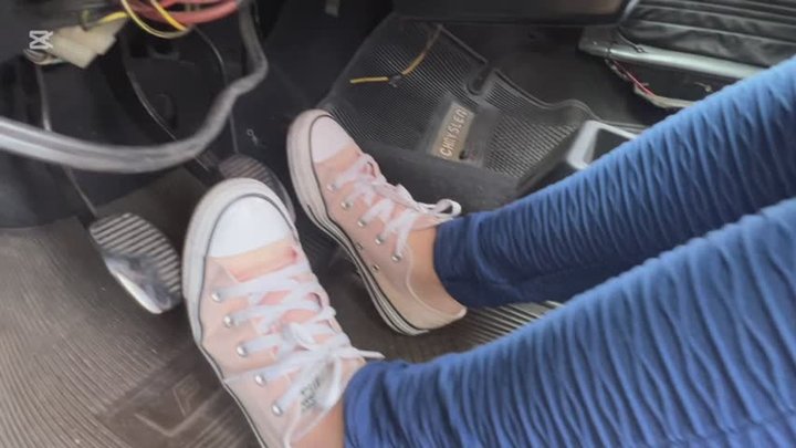 Jarlyn drives a car with many problems, wearing Converse sneakers and barefoot.