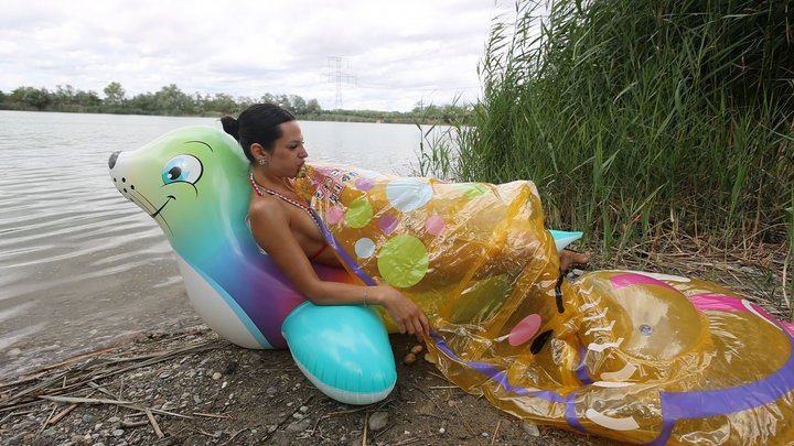 Jade blows two inflatables with her mouth on the lake